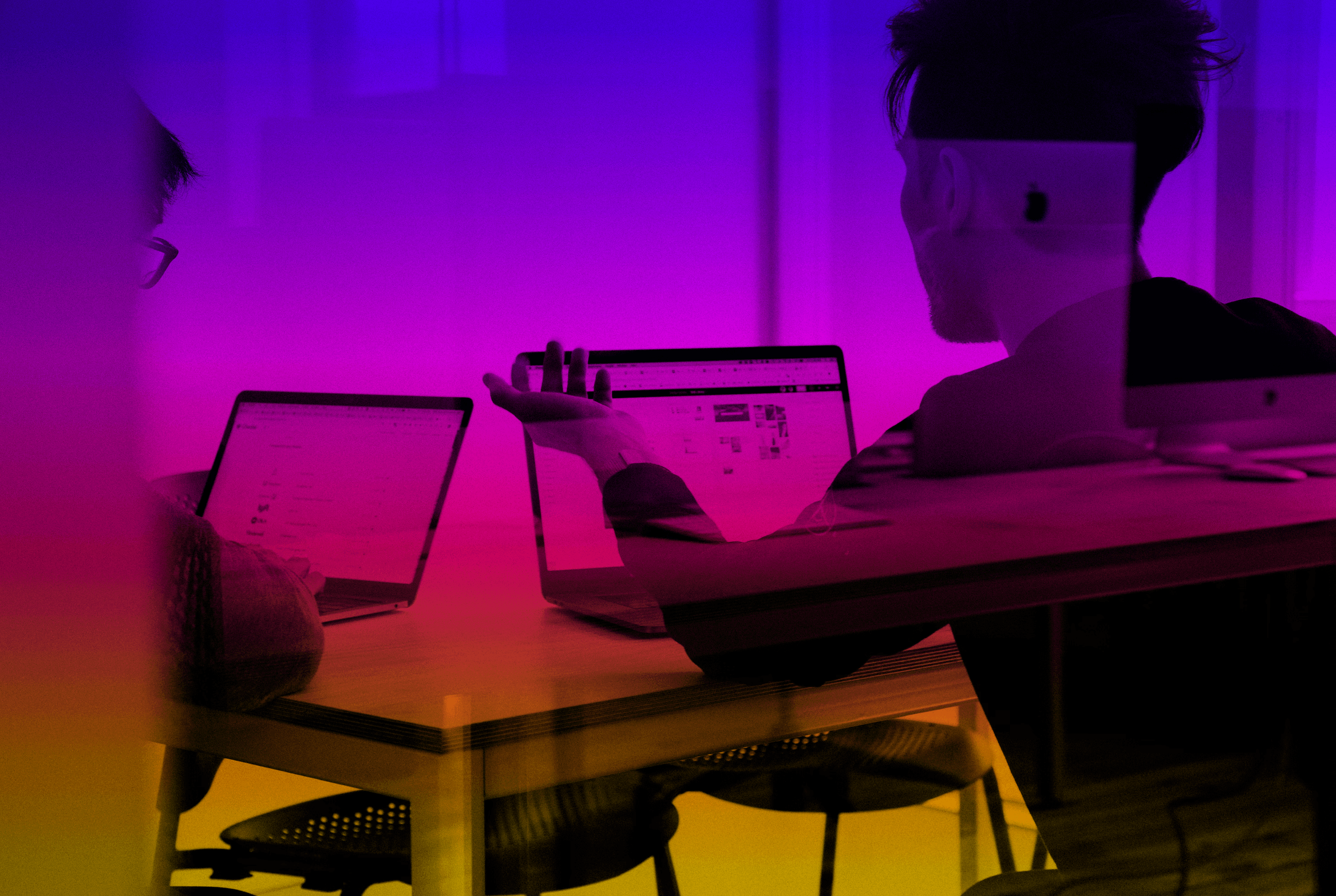 Two people collaborating on laptops with a vibrant purple and orange color gradient overlay.